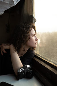 Side view of young woman looking through window