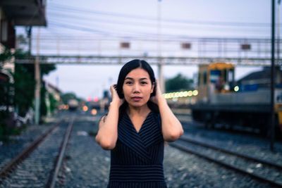 Portrait of young woman standing at railroad station