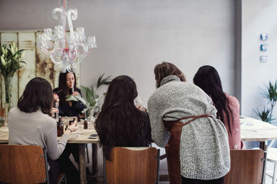 Multi-ethnic female colleagues preparing perfume at table in workshop