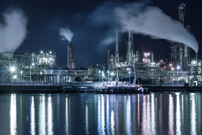 Illuminated factory against sky at night