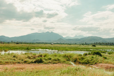 Scenic view of field with water source against sky and mountains 