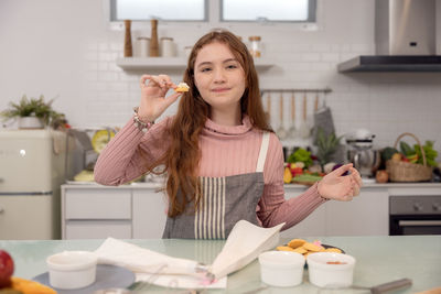 Portrait of woman holding food at home