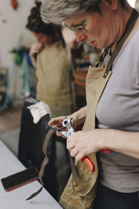 Entrepreneur making hole with equipment on leather belt