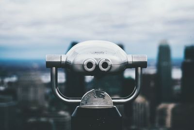 Close-up of coin-operated binoculars against cityscape