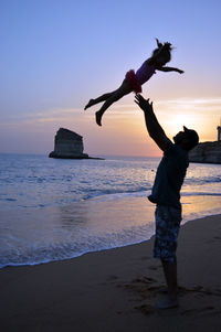 Man standing at beach against sky during sunset