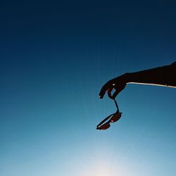 Low angle view of silhouette person against clear blue sky