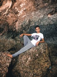 High angle portrait of woman sitting on rock