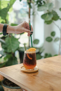 Midsection of person holding yuzu ice americano on table