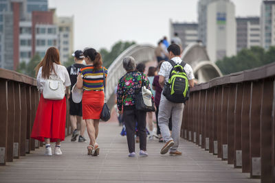 Rear view of people walking on bridge