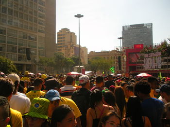 Crowd on city street by buildings against sky