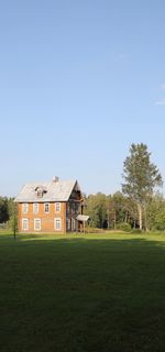 Houses on field by trees against sky