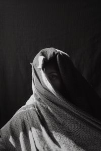 Portrait of man covering face against black background