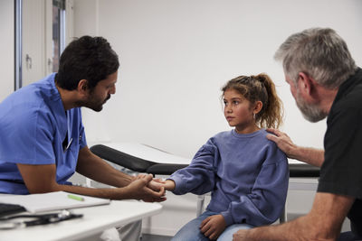 Male doctor examining girl patient's wrist during appointment