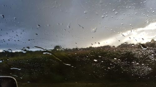 Close-up of wet window against sky