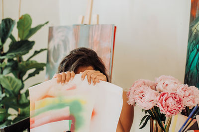 Female painter hiding behind a piece of paper in her art studio