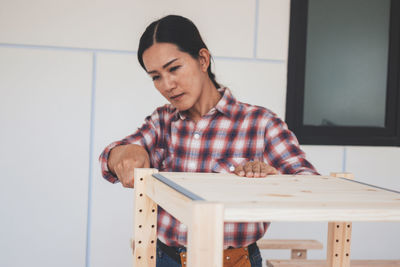 Portrait of a smiling young man holding table at home