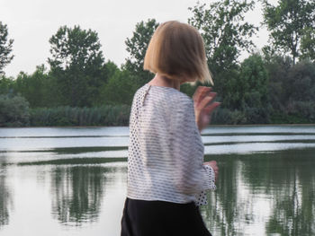 Rear view of woman standing against lake