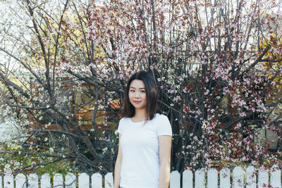 Portrait of smiling young woman standing against trees