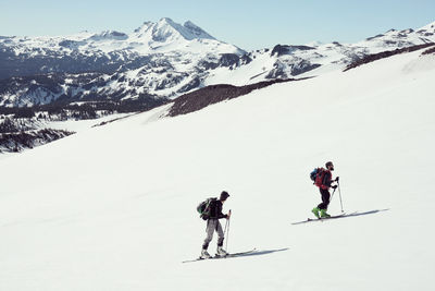 Male and female skiing with mountains in background