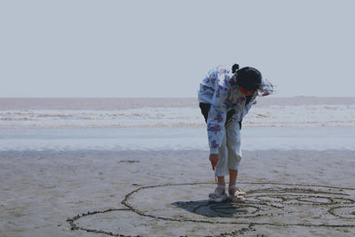 Full length of person on beach against clear sky