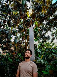 Portrait of young man standing against plants