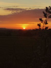 Scenic view of silhouette field against orange sky