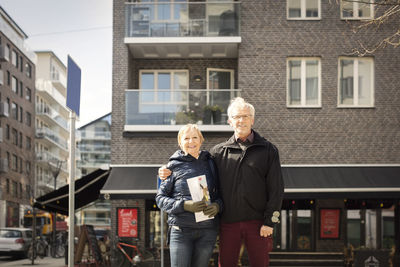 Portrait of smiling senior couple standing against building