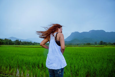 Woman standing in farm against sky