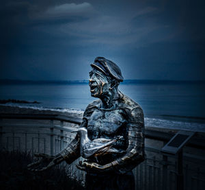 Statue by sea against sky