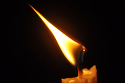 Close-up of lit candle in black background