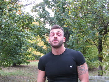 Portrait of young man standing against trees