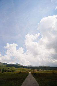 Road amidst field against sky