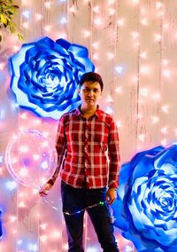 Full length of young man standing against illuminated blue wall