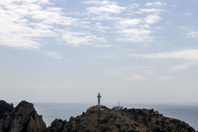 Lighthouse by sea against sky