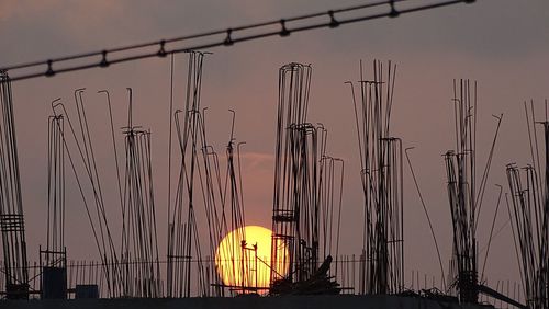 Illuminated ferris wheel in city against sky at sunset