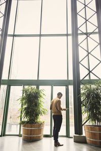 Rear view of woman standing by window