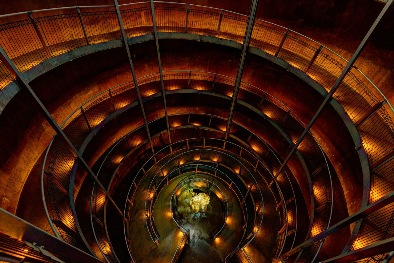 HIGH ANGLE VIEW OF SPIRAL STAIRCASE IN ILLUMINATED BUILDING