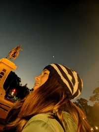 Portrait of young woman looking away against sky