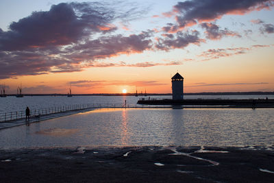 Pier over sea against sky during sunset