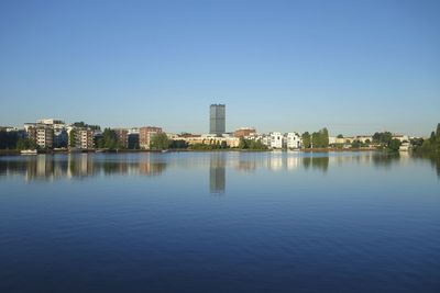 City by lake against clear sky