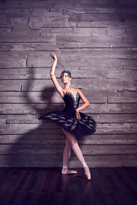 Full length of ballet dancer dancing on hardwood floor