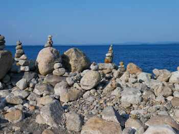 Rocks on beach against blue sky