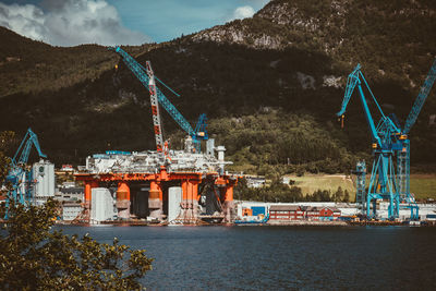 Cranes at commercial dock against sky