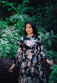 Portrait of young woman standing against plants