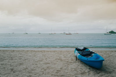 Sailboats moored on sea against sky