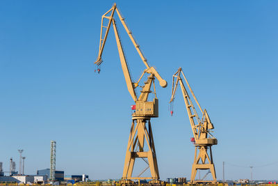 Low angle view of crane against clear blue sky