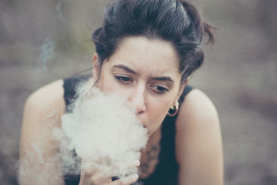 Close-up of young woman smoking outdoors