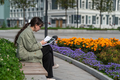 Portrait of young woman using mobile phone while sitting on bench