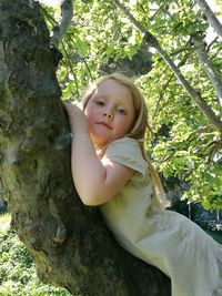 Portrait of happy girl standing against tree