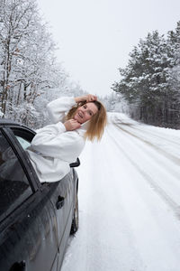 Portrait of young woman sitting on snow covered road